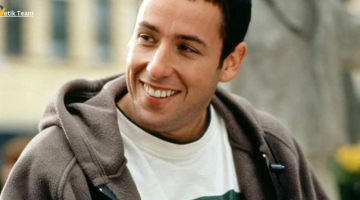 Pixelated face of Adam Sandler wearing a casual brown jacket and white t-shirt, with an outdoor background.